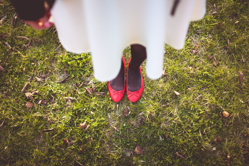 Mädchen in weißem Kleid und roten Ballerina-Schuhen